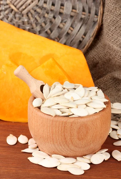 Pumpkin seeds in wooden bowl, on sackcloth background — Stock Photo, Image