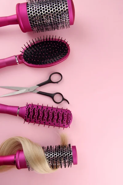 Comb brushes, hair and cutting shears, on pink background — Stock Photo, Image