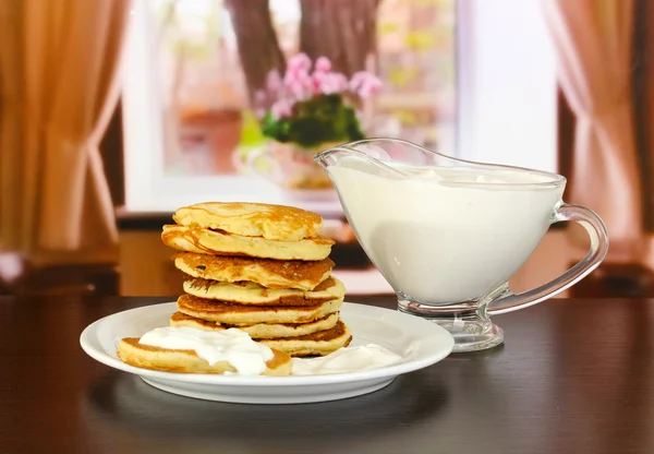 Crêpes sucrées sur assiette avec crème sure sur table dans la chambre — Photo