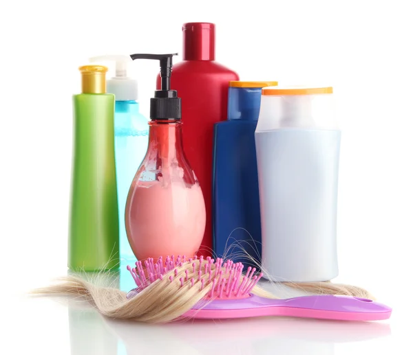 Escova de pente com cabelo e garrafas de cosméticos, isolado em branco — Fotografia de Stock