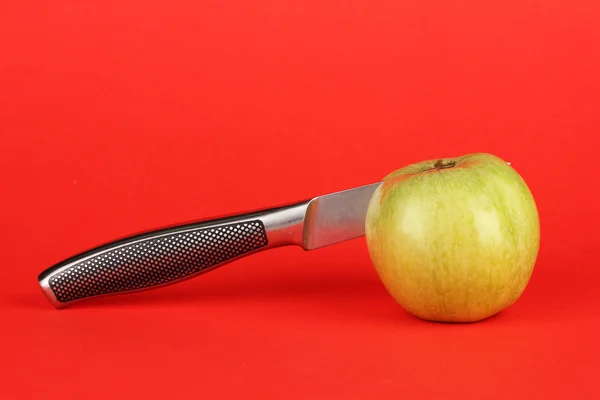 Green apple and knife on red background — Stock Photo, Image