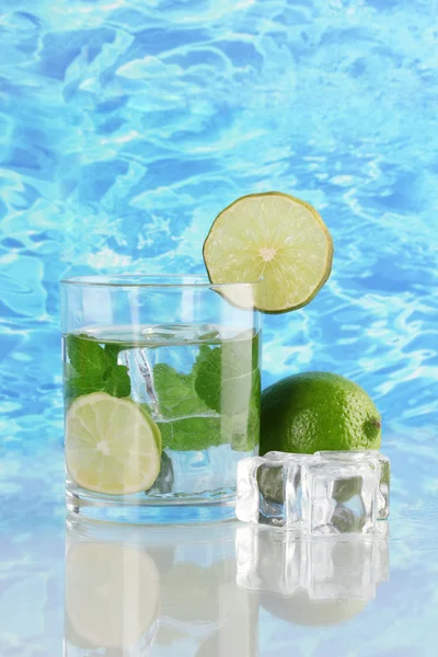 Glass of water with ice, mint and lime on sea background — Stock Photo, Image