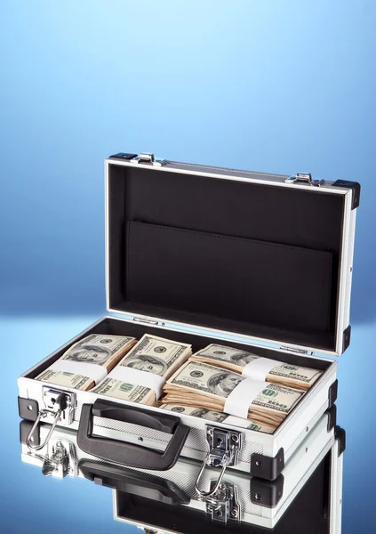 Suitcase with 100 dollar bills on blue background — Stock Photo, Image