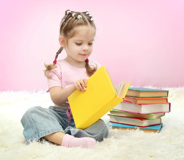 Cute little girl with colorful books, on blue background Royalty Free Stock Images