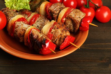 Lezzetli ızgara et ve sebzeler tabakta, ahşap masada.