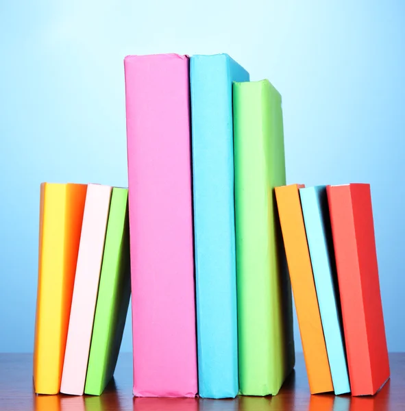 Pila di libri multicolore su sfondo blu — Foto Stock