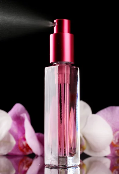 Vrouw perfume in mooie fles en orchideebloemen, op zwarte achtergrond — Stockfoto