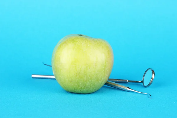 Grüner Apfel und zahnärztliche Werkzeuge auf farbigem Hintergrund — Stockfoto