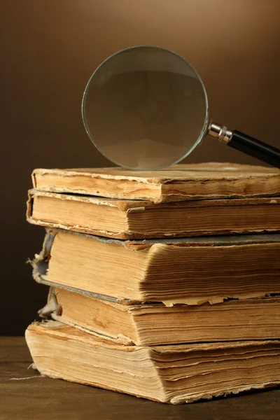 Magnifying glass and books on brown background — Stock Photo, Image