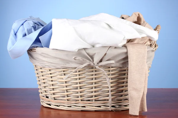 Roupas brilhantes na cesta de lavanderia, no fundo de cor — Fotografia de Stock