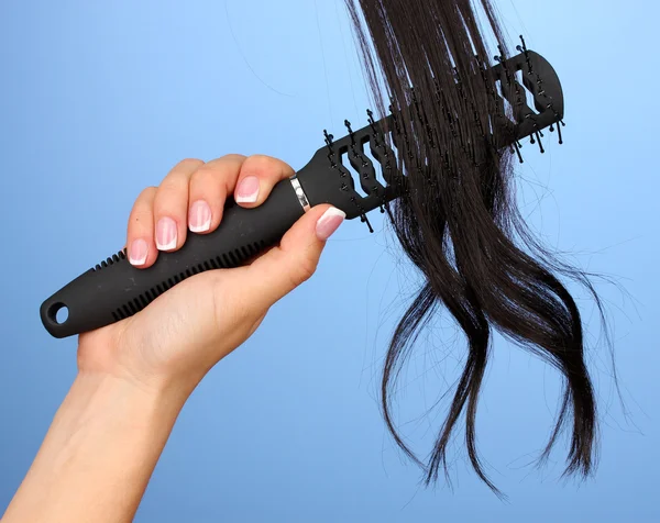 Dark curls brushing comb on color background — Stock Photo, Image