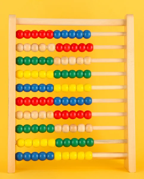 Abacus de brinquedo de madeira brilhante, no fundo amarelo — Fotografia de Stock