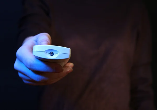 Mano de mujer sosteniendo un mando a distancia de TV, sobre fondo oscuro — Foto de Stock