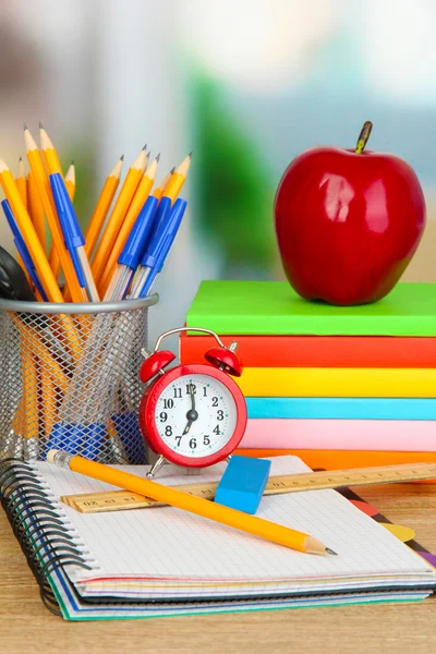 Schulbedarf mit Apfel und Uhr auf Holztisch — Stockfoto