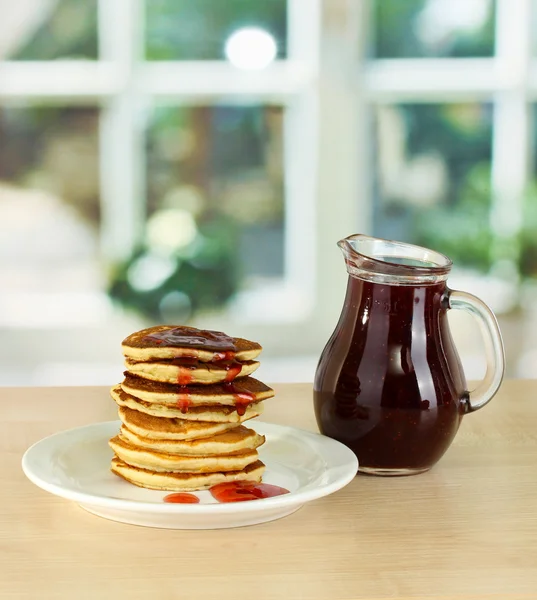 Sweet pancakes on plate with jam on table in kitchen — Stock Photo, Image