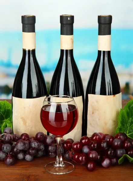 Склад пляшок вина, скла і винограду на яскравому фоні — стокове фото