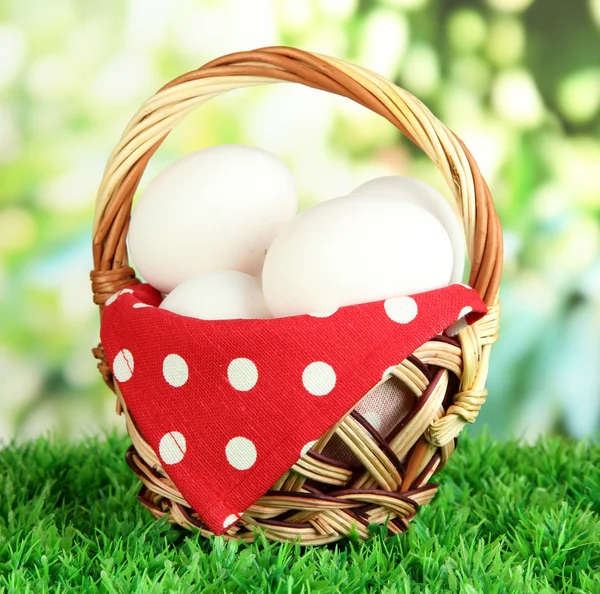 Many eggs in basket on grass on bright background — Stock Photo, Image