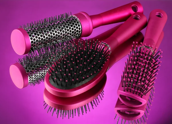 Comb brushes on purple background — Zdjęcie stockowe