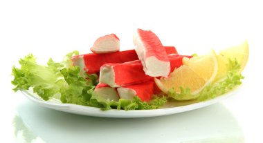 Yengeç sopalarla marul yaprakları ve plaka üzerinde beyaz izole limon