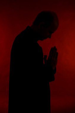 Genç papaz koyu kırmızı zemin üzerine