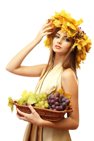 Hermosa mujer joven con corona de otoño amarillo y uvas en cesta, aislado en blanco — Foto de Stock