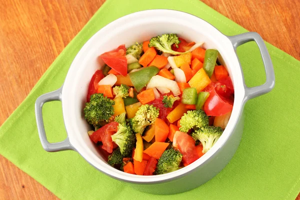 Ragoût de légumes en pot gris sur serviette de couleur sur fond en bois — Photo