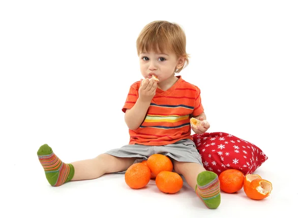 Schattige kleine jongen eten mandarijnen, geïsoleerd op wit — Stockfoto