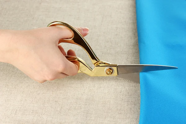 Seamstress corte tecido azul no fundo tecido bege — Fotografia de Stock