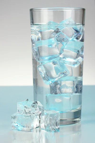 Cubos de hielo en vidrio sobre fondo azul claro —  Fotos de Stock