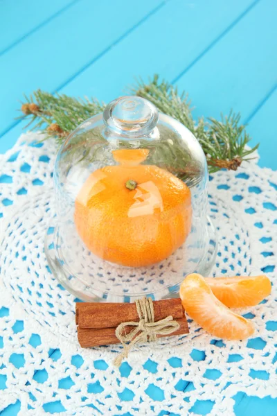 Tangerine sur soucoupe sous couvercle en verre sur fond bleu — Photo