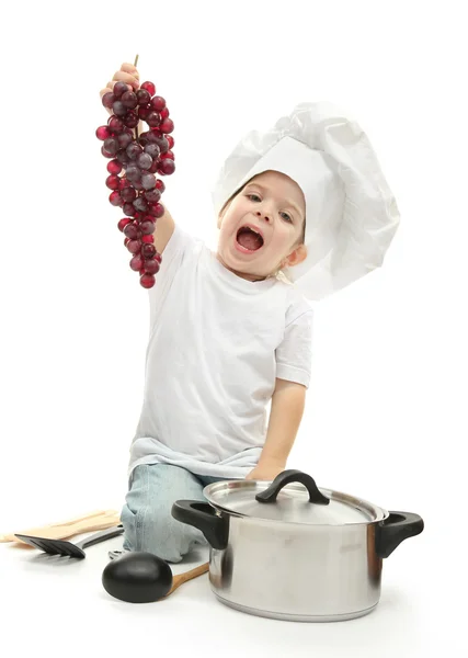 Κοριτσάκι στο καπέλο του σεφ με κουζίνα αξεσουάρ από σταφύλι, απομονωμένα σε λευκό — Φωτογραφία Αρχείου
