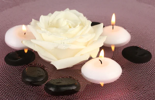 Piedras de spa con flores y velas en agua en el plato —  Fotos de Stock