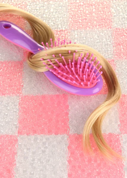 Cepillo peine con pelo sobre fondo de pared de baldosas rosa — Foto de Stock
