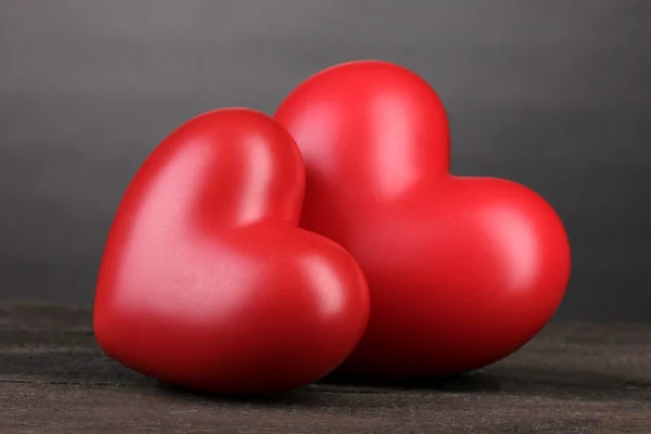 Dos corazones rojos decorativos sobre mesa de madera sobre fondo gris — Foto de Stock