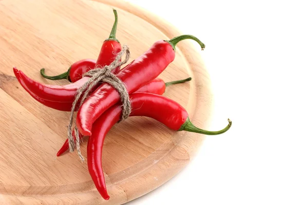 Red hot chili peppers tied with rope on wooden plank isolated on white — Stock Photo, Image