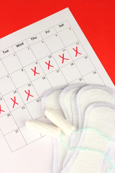 Calendario de menstruación con toallas sanitarias y tampones, primer plano —  Fotos de Stock