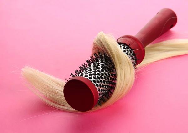 Hřeben kartáč s vlasy, na růžovém pozadí — Stock fotografie