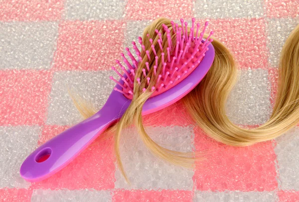 Cepillo peine con pelo sobre fondo de pared de baldosas rosa —  Fotos de Stock