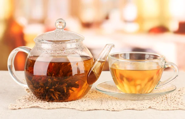 Té verde exótico con flores en tetera de vidrio sobre fondo brillante —  Fotos de Stock