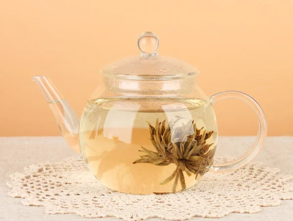 Exotischen grünen Tee mit Blumen in Glas Teekanne auf dem Tisch auf Farbhintergrund.Prozess der Teezubereitung — Stockfoto