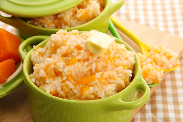 Taste rice porridge with pumpkin in saucepans on tablecloth background — Stock Photo, Image