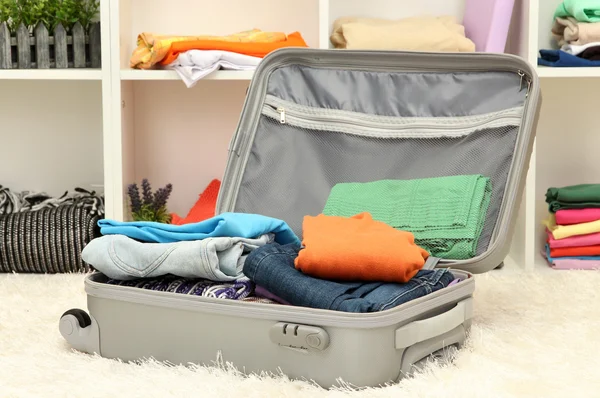 Valise ouverte grise avec vêtements dans la chambre — Photo