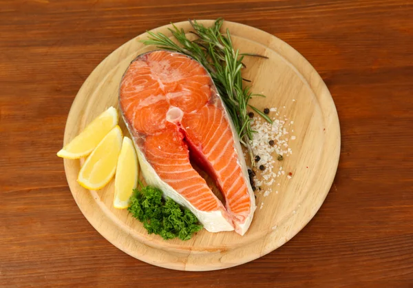 Fresh salmon steak on cutting board, on wooden background — Stock Photo, Image