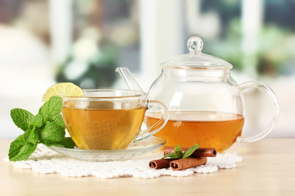 Cup of tea with mint,lime and cinnamon on table in room