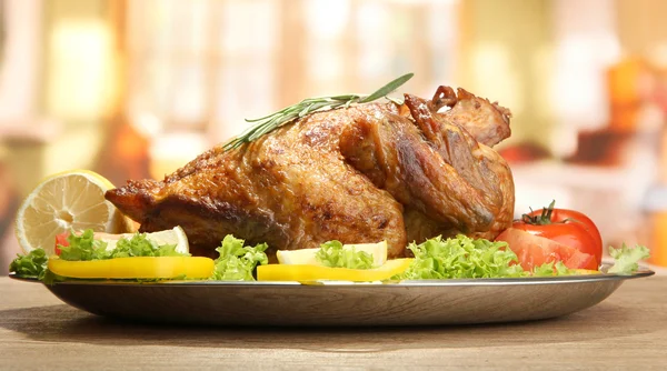 Poulet rôti entier avec légumes dans une assiette, sur une table en bois dans un café — Photo