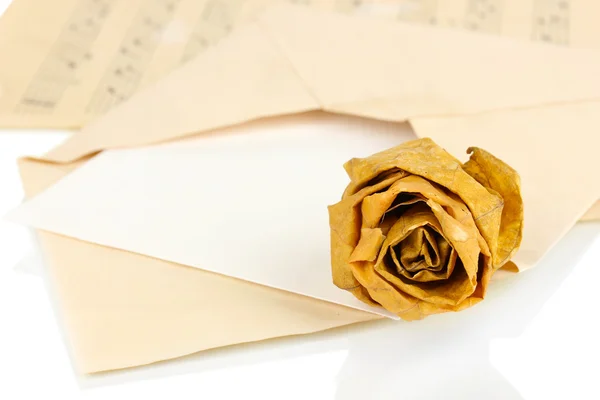 Vieille enveloppe avec papier blanc avec rose séchée sur des feuilles de musique close up — Photo