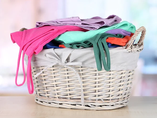 Clothes in wooden basket on table in room — Stock Photo, Image