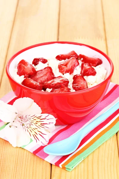 Τυρί cottage σε κόκκινο μπολ με φέτες τις φράουλες στο ξύλινο τραπέζι — Φωτογραφία Αρχείου