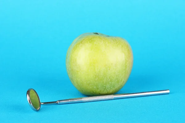 Green apple and dental tool on color background — Zdjęcie stockowe