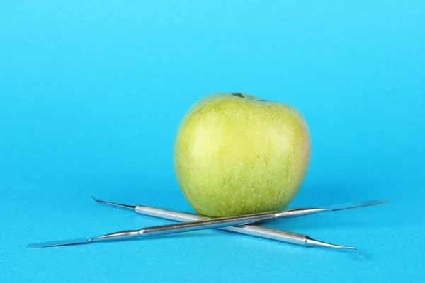 Green apple and dental tools on color background — Stock Photo, Image